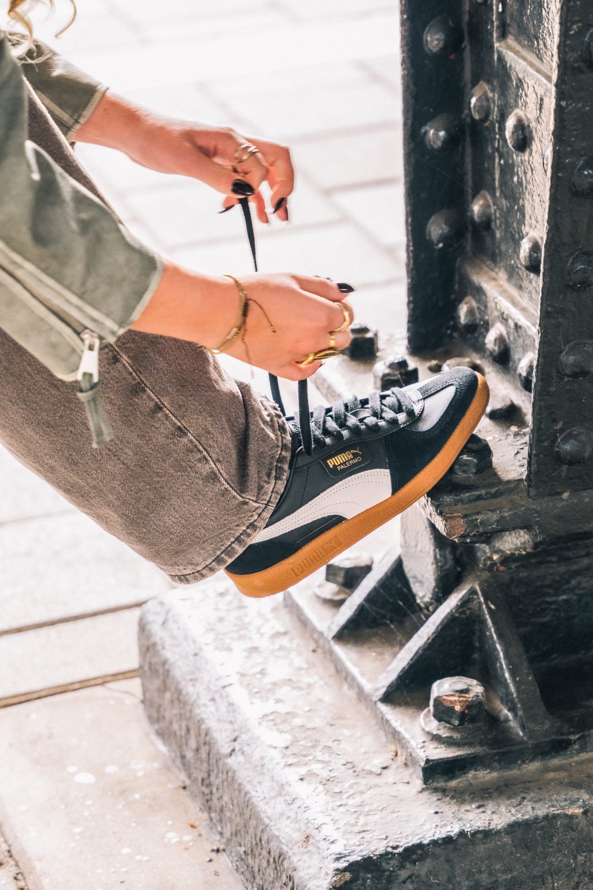 lacing up a puma palermo at a bridge pillar